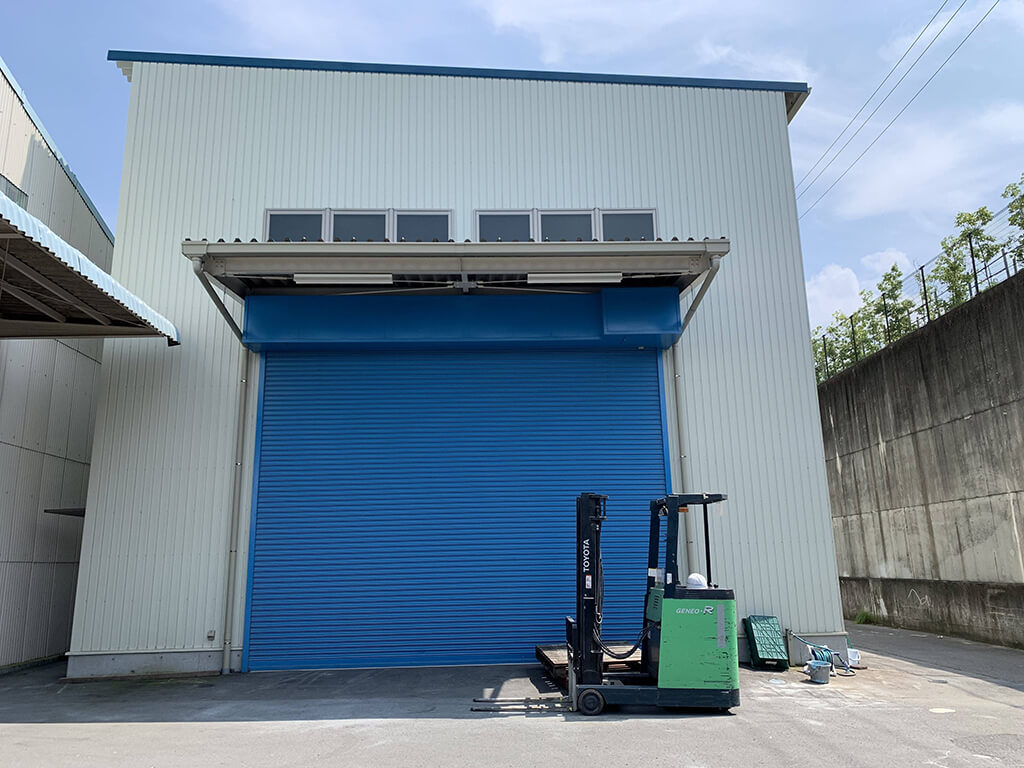 新塗装設備 白い壁と青いシャッターの屋外